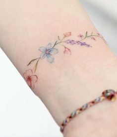 a woman's arm with a small flower tattoo on the left side of her arm