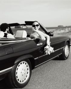 a woman sitting in the back of a convertible car