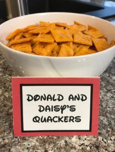 a white bowl filled with cheetos sitting on top of a counter next to a sign that says donald and daisy's crackers