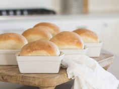 several loafs of bread in white dishes on a wooden tray