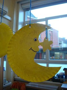 a yellow paper plate with a smiley face hanging from it's side in front of a window