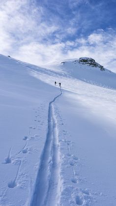 two people are hiking up a snowy hill