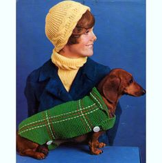 a woman wearing a green sweater and hat with a dachshund in it