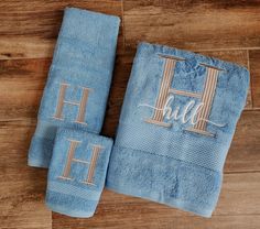 three blue towels with the word h on them sitting on a wooden floor next to each other