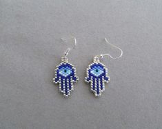 the hamsa earrings are made out of seed beads and have blue evil eyes on them