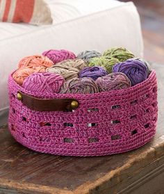 a basket filled with balls of yarn sitting on top of a wooden table