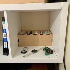 a white shelf with some cell phones and other items on it in front of a cardboard box