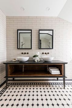 two sinks in a bathroom with black and white tiles