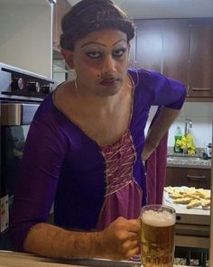 a woman in a purple dress holding a glass of beer and looking at the camera