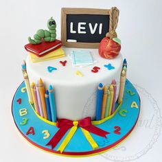 a birthday cake decorated with books, pencils and an apple