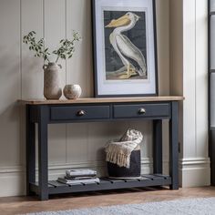 a black console table with two drawers and a white pelican painting on the wall