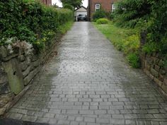 an empty brick road leading to a house