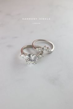 two engagement rings on top of a white marble surface with the words harmony jewels written above them