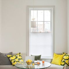 a living room filled with furniture and a glass table topped with oranges next to a window