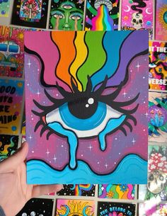 a person holding up a piece of art that looks like an eye with rainbow colors