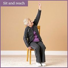 an elderly woman sitting on a chair with her hand up in the air and saying sit and reach