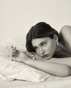 a black and white photo of a woman laying on a bed with her arms crossed