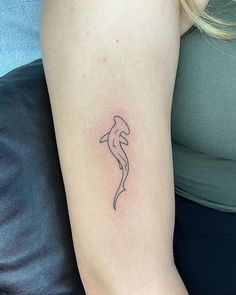 a woman's arm with a small dolphin tattoo on the left side of her arm