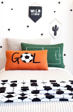 a bed with black and white stars on the wall behind it is decorated with soccer themed pillows