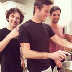 two men are cooking in the kitchen and one is pointing to something on the stove