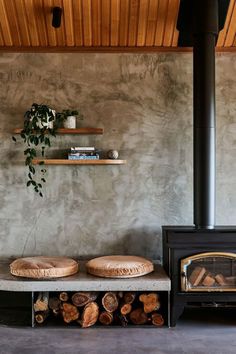 a fireplace with logs stacked on top of it in front of a wall mounted wood burning stove