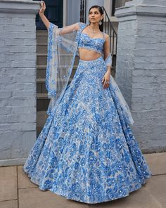 This lehenga set features powder blue three-dimensional floral embroidery, highlighted with crystals, pearls, and sequins on an ivory base. The waist of the blouse is scalloped and shows crystal drops. It is paired with a four-sided embroidered dupatta.From Seema Gujral's For the love of London collection. DELIVERY TIMEPlease allow 8-12 weeks for your outfit to arrive. FABRIC DETAILSNet Professional cleaning only. Pretty Indian Outfits, Elegant Blue Lehenga With Sequins, Blue Sequined Sets For Reception, Designer Blue Lehenga With Sequins, Designer Blue Sequined Lehenga, Elegant Blue Choli With Sequins, Blue Sequined Sets For Wedding, Blue Sequined Wedding Set, Glamorous Blue Sets For Festive Occasions