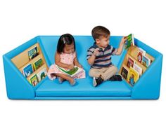 two children sitting on a blue couch reading books