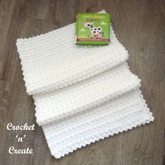 a crocheted cloth is laying on the floor next to a green and white book