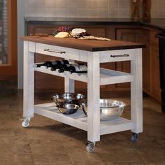 a kitchen island with wine bottles and bowls on it in the middle of a room