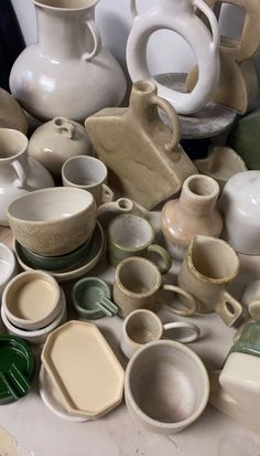 a pile of white and green pottery sitting on top of a table next to each other