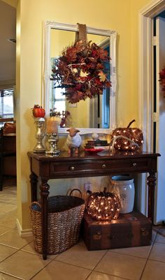 an entryway with a table and mirror in it, decorated for fall or halloween