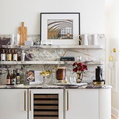 a kitchen with marble counter tops and wine glasses on the top shelf next to it