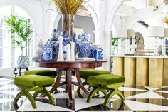 a dining room table with green chairs and blue vases on the top of it