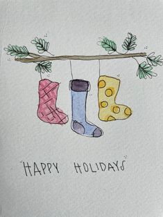 three socks hanging on a branch with the words happy holidays written below them and pine branches