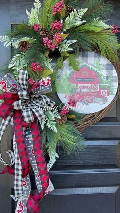 a christmas wreath on the front door with red and black plaid ribbon tied around it