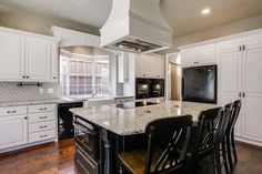 a large kitchen with white cabinets and black appliances