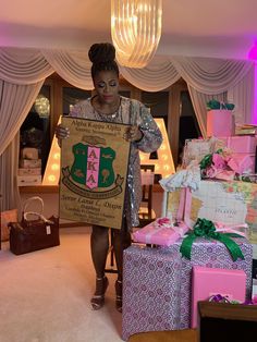 a woman is holding a sign in her hand while walking through a room filled with presents