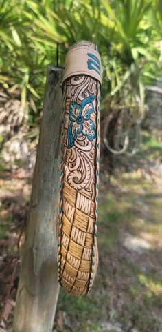 a close up of a wooden object on a tree branch with plants in the background