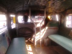 the interior of a bus with several seats and two people sitting on one seat, looking out the window