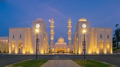 a large white building with two clocks on it's sides and lights at the top