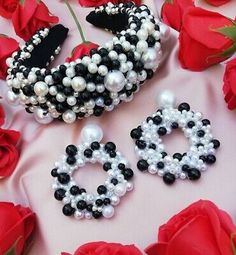 two pairs of black and white beaded earrings on pink fabric with red roses in the background