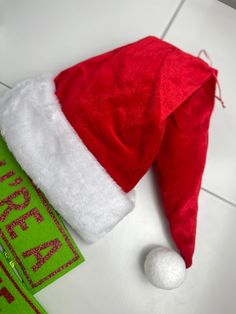 a red and white santa hat sitting on top of a tile floor next to a green sign