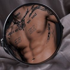 a man's chest is reflected in a round mirror with tattoos on his back