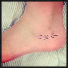 a small cat's face tattoo on the foot