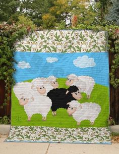 a quilt with sheep on it in the grass