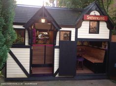 the outside of a small store with black and white shingles on it's sides