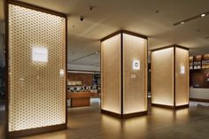 an empty room with wooden partitions and lights on the walls, in front of bookshelves