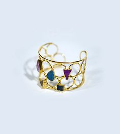 Elevate your style to celestial heights with our Multicolored Amethyst Gold Bangle. Handcrafted with precision and care, this cuff bangle is a mesmerizing blend of elegance and charm, destined to make you feel like royalty. Indulge in the enchantment of this geometric masterpiece, adorned with twinkling zircon stones in a spectrum of colors. Each stone, left unpolished to preserve its natural beauty, adds a whimsy to your ensemble, making every moment magical. The lustrous rhodium plating enhances the brilliance of the stones, ensuring that you shine like a star wherever you go. Plus, with its sliding clasp design, adjusting the bracelet to your perfect fit has never been easier. Crafted from high-quality brass and zircon stone, this bangle is not only a fashion statement but also a symbol Amethyst Bangle, Geometric Bangle, Handmade Bangles, Amethyst Gold, Gold Bangle, Gold Plated Bracelets, Stone Gold, Cuff Bangles, Gold Bangles