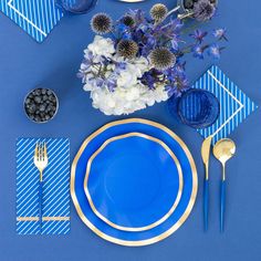 blue and gold place setting with flowers on the plate, napkins and spoons