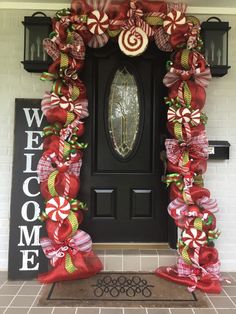 the front door is decorated for christmas with candy canes and bows on red ribbons